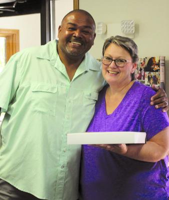 DEON FIELDS (left) brings Felicia Farabee fresh-baked cookies on her last day at Central Missouri Community Credit Union after 20 years of service. SHARON DONAT | Staff