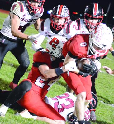RYAN SHARP (left) hangs onto Richmond teammate Nolan Quick as a swarm of Hornets converge on them following Chillicothe’s fourth-quarter onside kick attempt in district 11-man football action. SHAWN RONEY | Staff