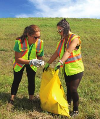 VANESSA CLARK lifts debris from Highway 13. Her sister, Alisha Brandham, holds open the bag. J.C. VENTIMIGLIA | Staff