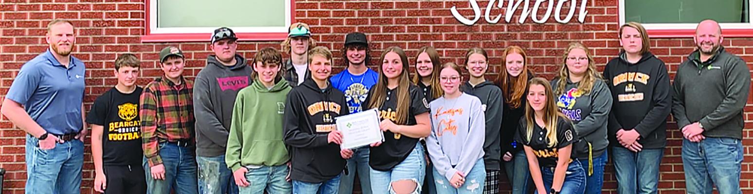 HIGGINSVILLE AREA FCS Financial Vice President Andrew Homfeld (left), awards grant to OHS FFA students Jacob McElwee, Elye McElwee, Maddox Peterson, Luke Smith, Gunner Smith, Cash Honeycutt, Hunter Spear, Isabel Wheeler, Natasha Hicks, Elana Boude, Aerin Cook, Natalie Williams, Hailey Haun, Shelbie McElwee and Dallas Lynn with Higginsville area FCS Financial Assistant Vice President Mike Mason. The team plans to upkeep the Ray County Fairgrounds. Submitted