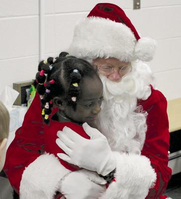 SOPHIA BALES | Staff RIVER SISSON-DODSON hugs Santa Claus as her classmates make their way back to their classroom after story time.