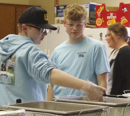HUNTER HOLLOWAY (from left) serves food alongside Isaac Kaylor as Sarah Brown helps coordinate meal preparation during a student-led community event. MIRANDA JAMISON | Staff