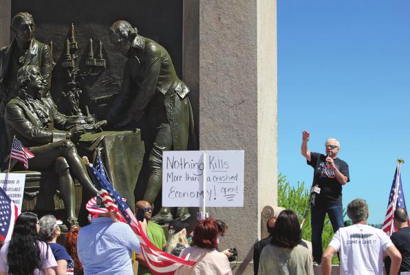 RADIO SHOW HOST Dave “Super Dave” Day warms up the Reopen Missouri crowd of about 500 people at the “Signing of the Treaty” sculpture on the Capitol grounds Tuesday in Jefferson City. Several crowd members carry signs that denounce Gov. Mike Parson for issuing a stay-home order.