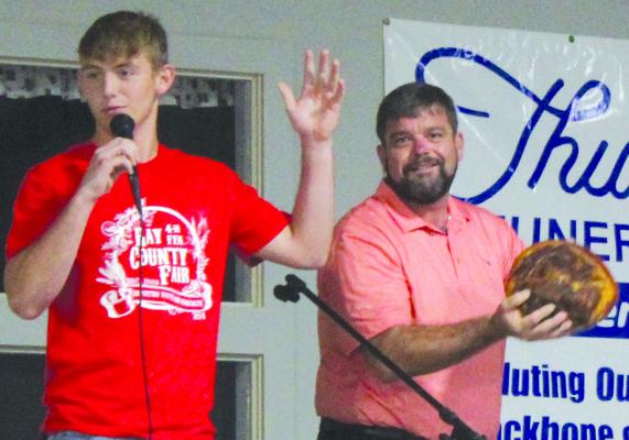 JUSTIN WRISINGER (right) hands Xavior Gaskins of Orrick FFA the mic to auction off his ham. SHARON DONAT | Staff