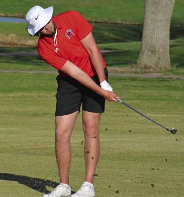 SENIOR JACK GOGUE stirs up tufts of fairway as he hits a chip shot late in Tuesday’s triangular with Lexington and Carrollton at Shirkey Golf Course. SHAWN RONEY | Staff