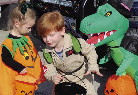 KATRINA RICHARDS (left) watches Asher Hazelman run from the dino during the event. SHARON DONAT | Staff