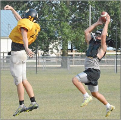 JEFF ROHDE (right), who normally plays quarterback on offense, gets in some time at receiver and nabs a pass while covered by Orrick teammate Logan Dennis Tuesday on the school’s practice field. SHAWN RONEY | Staff