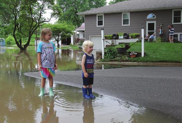 WITH WEST FORK of Crooked River overflowing, 6-year-old Ryann Madget and Reis Madget, 2, wear boots June 25 while standing in the water on Brookwood Street.