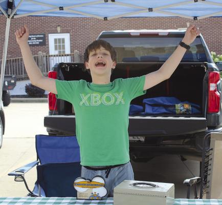 LOGAN SHELTON enthusiastically greets visitors at his popcorn booth. See more on Page 7 of today’s edition. SHARON DONAT | Staff