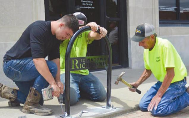 INSTALLING BIKE RACKS around Richmond’s downtown square are James Schwartz, Sean McCarter and Mike Outersky. Matching park benches are next. TARA ALTIS | Staff