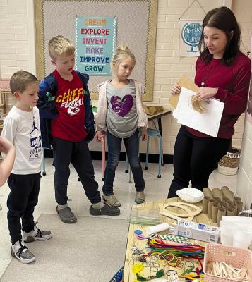 COOPER TRINDLE (from left), Remy Judd, Natilynn Stephens and Dear Elementary technology teacher Brittany Vest look through materials to make ‘zip lines’ through a STEM curriculum formatted by Vest. The first-graders are excited to start the designing process. SOPHIA BALES | Staff