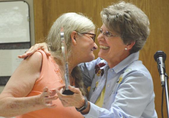 SISTERS Karen Grantham, left, and Linda Dawson embrace late in the ceremony honoring Charley, Eugene and Garold Skiles. The men will be remembered on the first Sunday in June and with a bridge in their name. SHAWN RONEY | Staff