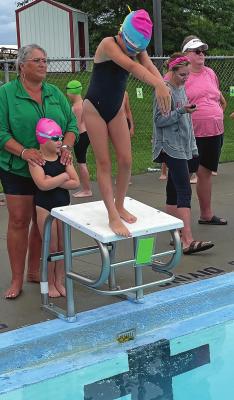 HADLEY BURGESS gets ready to jump off the block during the Dolphins’ swimming meet July 10 at Southview Pool in Richmond. Behind her are teammate Deliah Fewins and coach Angela Pencook. SUBMITTED Photos