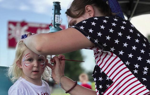 SAGE NIEMEIER sits still for her face painting of red, white and blue fireworks. JOSHUA BRUNGARDT | Staff