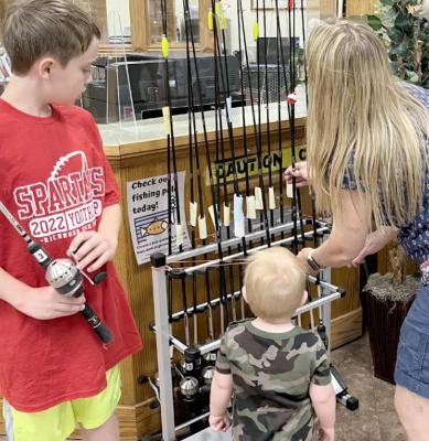 ISAAC, 10; Sam, 2; and Susan Duffett are sizing up the library’s newest item: fishing poles. SOPHIA BALES | Staff