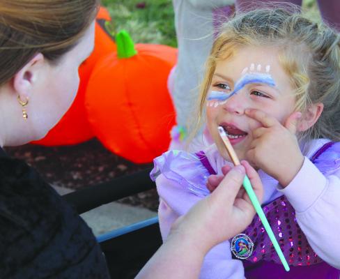 EMMERSON ATKISON directs the placement of her next face painting dot during the Hardin Fall Fest. SHARON DONAT | Staff