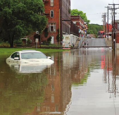 AS SEEN from the South Marietta Street Bridge in downtown Excelsior Springs, flood water spills out from the Fishing River and covers the north side of the street, where this Lincoln remains surrounded after the driver is rescued around 6 a.m. June 24 by city emergency personnel. Flood water inundates lots that would have been used for WaterFest parking and traps vehicles already parked there. J.C. VENTIMIGLIA | Staff