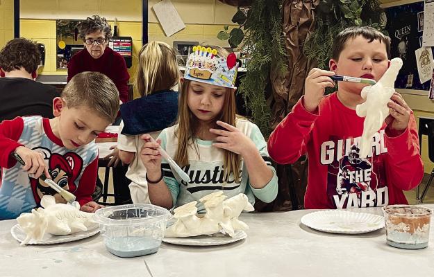 COOPER TRINDLE, ASPEN WEIR and Bentley Stephens glaze the clay dinosaurs they’re creating at Dear Elementary Clay Night. Each takes direction from Dear art teacher Bea Hendrix, who explains how to get coverage. See page 2 for the story. SOPHIA BALES | Staff