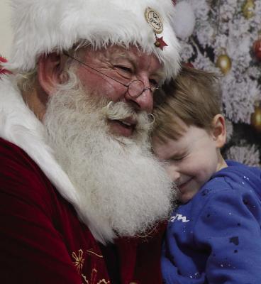 LANDON HARVIE wraps his arms around Santa, sharing a warm hug that shines with the magic of the holiday season. SHARON DONAT | Staff