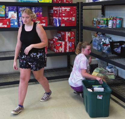 VOLUNTEERS: From left, Lily Wirsig and Allie Renfro work to stock the shelves at the Richmond United Methodist Church with GAP items for the new distribution facility at the church. Not pictured are volunteers Zane Renfro and Stephen Slater. Cathy Myers | Submitted