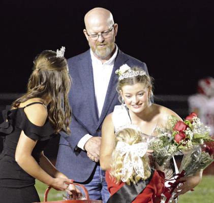 GRACE BOZARTH (from left), Richmond’s 2023 homecoming queen, and Bill Dooley watch as Isabelle Dooley receives flowers after being crowned the 2024 Richmond High School Homecoming Queen recently. SHAWN RONEY | Staff