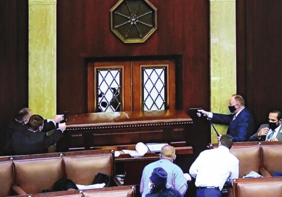 INSIDE THE U.S. HOUSE, law enforcers draw sidearms to prevent entry by insurrectionists.