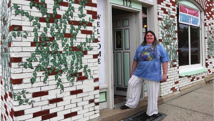JENIFER DICKSON stands in the doorway of Bark Bargains, 112 S. College St., Richmond. The storefront is designed to catch the eye with the bricks painted white and red, and the leaves painted over bricks.