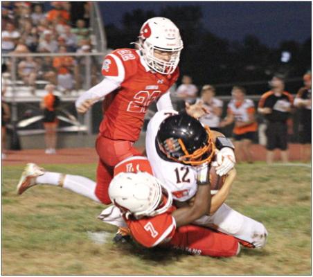 RICHMOND JUNIOR CHRIS WEBB (No. 7) tackles Oak Grove’s Jordan Hall as fellow Spartan Will Robinson closes in Sept. 1 at Richmond. SOPHIA BALES | Staff