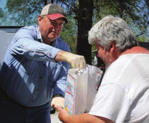 COMMISSIONER Allen Dale delivers bags of food to Jonathon Reavis. The Ray County Senior Center makes home deliveries to make sure older residents can get food after the center closes because of COVID-19.