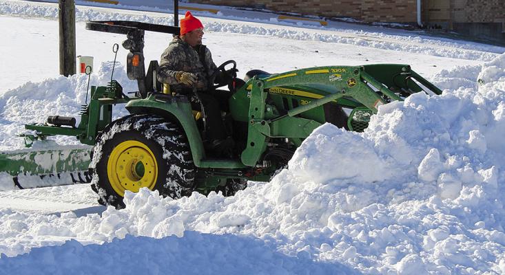 A CITY WORKER pushes snow onto the corner of West North Main and North Camden. SHARON DONAT | Staff