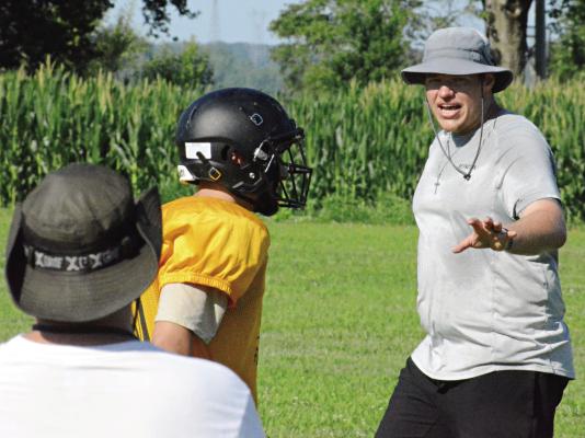 ORRICK ASSISTANT COACH Chase Sims (right) explains assignments and techniques as the Bearcats install their new defense during varsity team camp Monday on the Orrick practice field. SHAWN RONEY | Staff