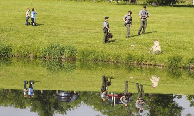 REFLECTIONS RIPPLE ACROSS the pond as children, conservation staff and first responders spread out along the shoreline for a morning of fishing and outdoor activities. SHARON DONAT | Staff