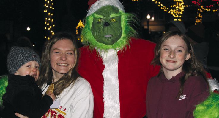 WHILE SNEAKING around the square, the Grinch stops for a photo opportunity with Elijah and Amanda Hall (left) and Daysyn Miller. SHARON DONAT | Staff