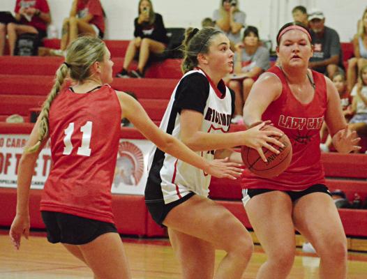 WITH THE BASKETBALL in both hands, Richmond’s Emma Hash looks to split through two Braymer defenders Monday in River Valley Shootout action at Carrollton. SHAWN RONEY | Staff