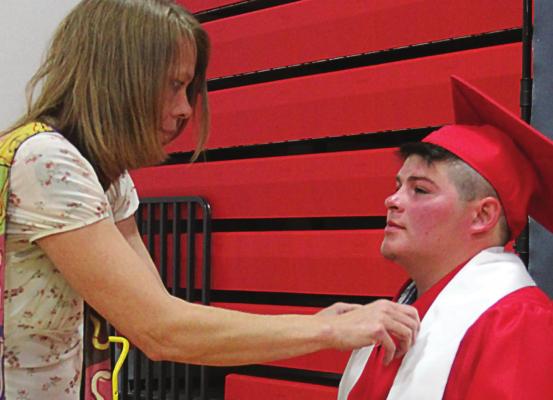 IN PREPARATION for a portrait photo, Kathy Troxel helps son Ryan Graham with his graduation garments.