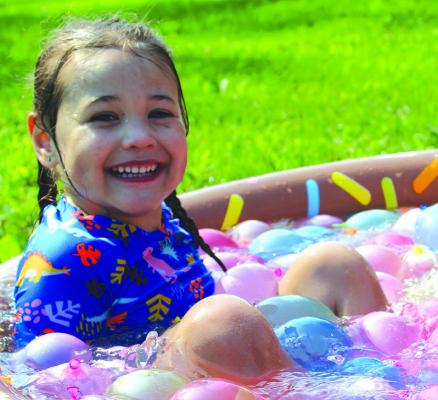 RYAN JONES takes a break in a pool full of water balloons during the CAP water balloon fight in the park. SHARON DONAT | Staff