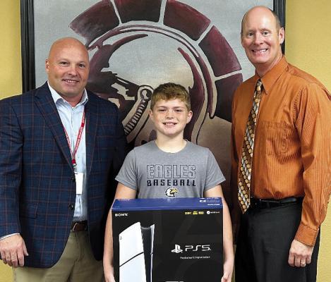 RICHMOND SCHOOL District Assistant Superintendent Trey Cavanah (left) and Superintendent Dr. Bryan Copple (right) present the PS5 to raffle winner Jaxx Hicks. Submitted