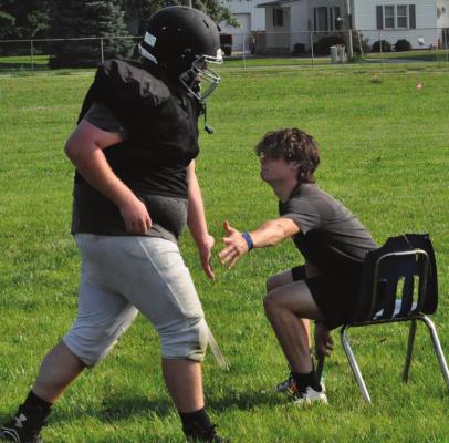 SENIOR BRAYDEN SCHICK gives a low-five to Norborne Hardin-Central teammate Carson Penny while Penny runs wind sprints Monday. SHAWN RONEY | Staff