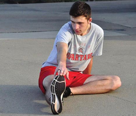 SHELDON GOEDEKE stretches Aug. 17 in preparation for cross country season. SHAWN RONEY | Staff