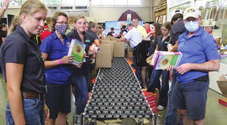 AT THE MISSOURI State Fair, at the front, left and right, are Isabella Kamler and Mark Gunby. They pack boxes for Missouri families in need of food. J.C. VENTIMIGLIA | Staff