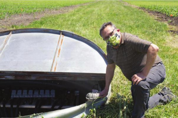 AMY MEYER | Harvest Public Media USDA microbiologist Tom Moorman kneels beside the collection system that segregates water from unique drain lines placed under 24 plots.