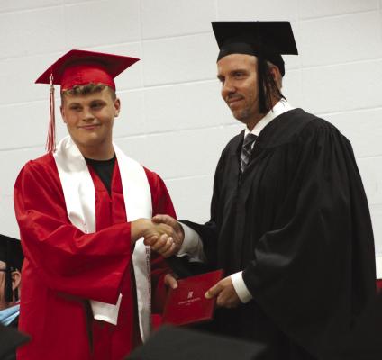 ETHAN HALL (left) shakes hands with Board of Education President Jon Dana during the commencement.