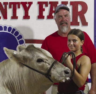 KINLEY CALVERT holds the cow’s lead for the auction.
