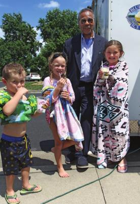 FREE ice cream for everyone at the Higginsville pool is gobbled by Dax Plymell, 4, and his sisters, Ellie Ryun, 6, and Marley Plymell, 6. Behind them, U.S. Rep. Emanuel Cleaver II pays for the ice cream while making sure parents know there is money in the mail coming for school-age children. J.C. VENTIMIGLIA | Staff
