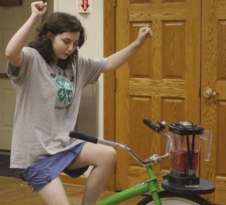ELSIE ARNOLD pedals a bicyclepowered blender during a recent 4-H program, demonstrating the use of humanpowered energy to make a fruit smoothie. SHARON DONAT | Staff