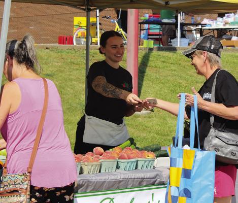 BEV HOLLOWAY purchases peaches at Summer Bash. SHARON DONAT | Staff