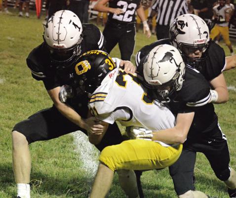 BEFORE BEING crowned a homecoming king, Kalel Bowman (No. 1) helps his fellow Aggies take down Orrick ballcarrier Jeff Rohde. SHAWN RONEY | Staff