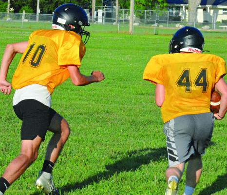 PARKER FLOYD (left) pursues running back Ozzden Ayers as Orrick runs through the circle drill during an offseason camp session. SHAWN RONEY | Staff