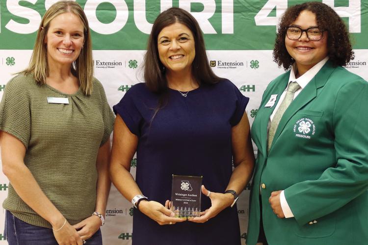 MISSOURI 4-H FOUNDATION Board of Trustees member Wendy Hall (left) and State 4-H Council Vice-President Aaliyah Higgs (right) present the auctioneer of Wrisinger Auctions, Heather Pugh, a plaque honoring their induction into the Missouri 4-H Hall of Fame. AMANDA STAPP | Submitted