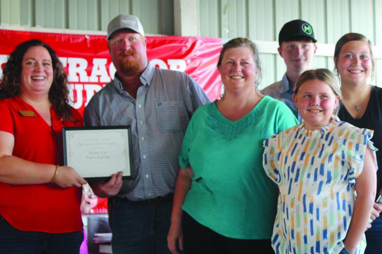 EXTENSION ENGAGEMENT SPECIALIST Chelsea Corkins (left) presents the 2024 Ray County Farm Award to Jeremy McGinnis and family, including wifem Jamie, and children Kaden, Amaryllis and Kassie. SHARON DONAT | Staff